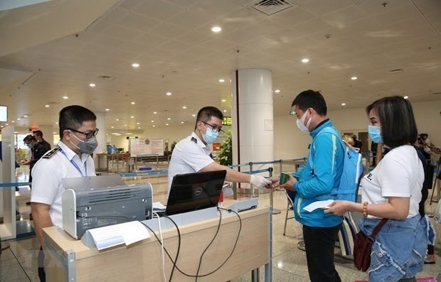 Customs officers check passengers' documents at Noi Bai airport. (Photo: VNA)