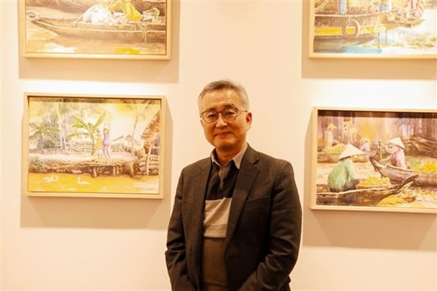 Kim Jai-min, a retired teacher in the Republic of Korea (RoK), stands next to his paintings on Vietnam. (Photo: VNA)