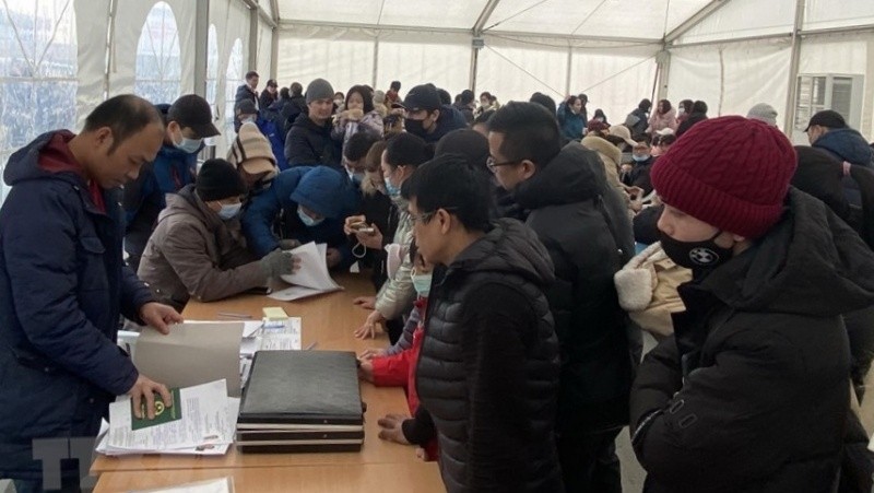 Officials of the Vietnamese Embassy in Romania handle procedures for Vietnamese in Ukraine to return home at the airport of Bucharest, Romania. (Photo: Manh Hung/VNA)