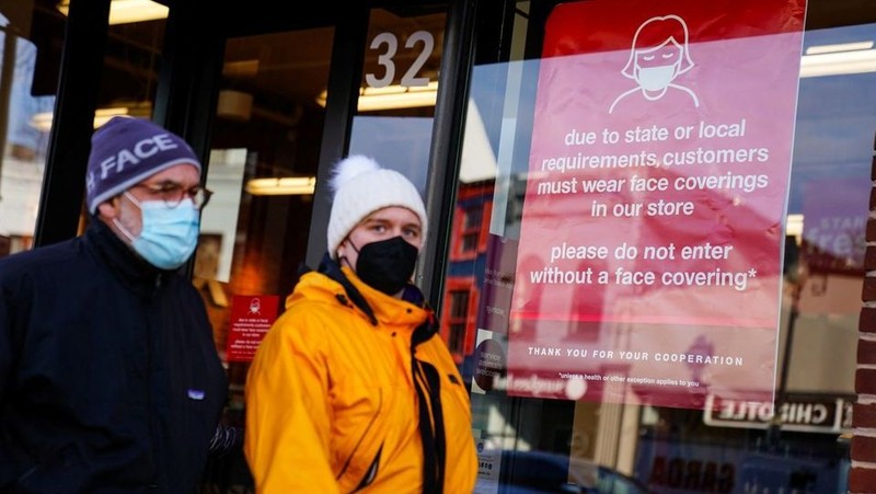 People wearing protective face masks walk past a business displaying a sign requiring face coverings during the COVID-19 pandemic in Washington, US. (Photo: Reuters)