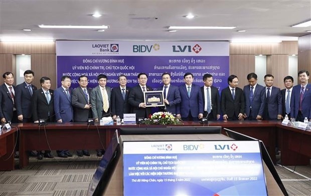 NA Chairman Vuong Dinh Hue (eighth from left) presents a gift to a representative of the Lao - Viet Bank on May 15. (Photo: VNA)