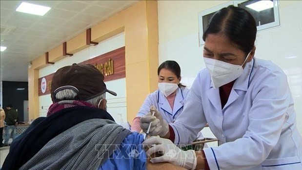 Health workers administer COVID-19 vaccine shot for a senior citizen.(Photo: VNA)