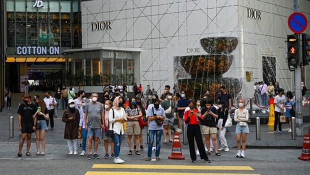 People wait before crossing a road in front of a shopping mall in Kuala Lumpur on Jun 2, 2022. (Photo: AFP)