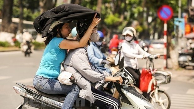 Motorcylists cover themselves with thick clothing to avoid the heat. (Photo: VNA)