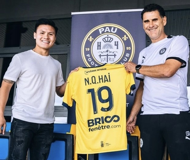 Vietnam's international Nguyen Quang Hai (left) poses with his new coach Didier Tholot and jersey, after signing a two-year contract with French side Pau FC on June 26. (Photo of Pau FC)