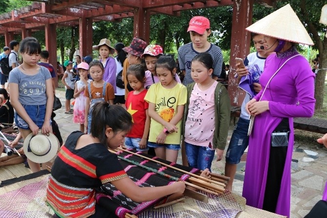 Children learn about traditional weaving crafts at Vietnam National Village for Ethnic Culture and Tourism (Photo: langvietonline.vn)