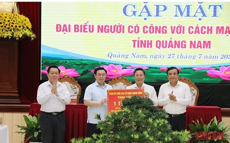 NA Chairman Vuong Dinh Hue presents the token of 1 billion VND (42,720 USD) supported by the Party Committee of the Central Agencies' Bloc to build houses for people with meritorious services in Quang Nam province. (Photo: NDO)