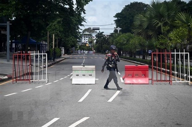 A member of the Myanmar security forces walks by a checkpoint in Yangon on July 19, 2022. (Photo: AFP/VNA)