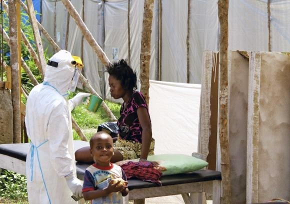 A health worker, wearing personal protection gear, offers water to a woman with Ebola virus disease (EVD), at a treatment centre for infected persons in Kenema Government Hospital, in Kenema, Eastern Province, Sierra Leone in this August, 2014. (Credit: Reuters/Dunlop/UNICEF)