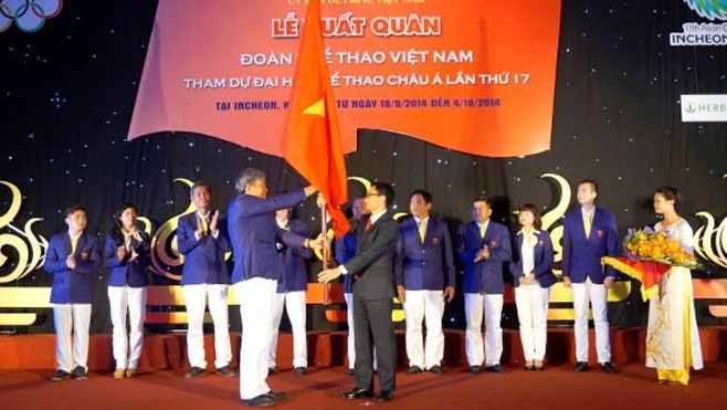 Deputy PM Dam (right) hands over the national flag to head of the Vietnam sports team, Lam Quang Thanh. (Credit: CPV)