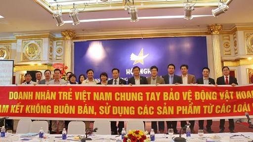 Representatives of young entrepreneurs hold a slogan of their commitments to support wildlife conservation. (Credit: moitruong.com.vn)