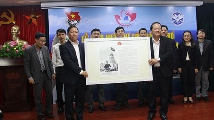 Deputy Minister of Information and Communications Truong Minh Tuan presents the maps and documents to representatives of young generations. (Credit: tienphong.vn)