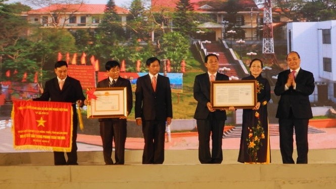 Deputy PM Phuc presents the government’s emulation flag, ‘new-style rural district’ certificates to the town's Party, government and people.