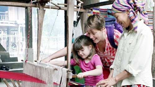 Foreign visitors experiment weaving brocade with Thai people during a home stay tour in Lac village in Mai Chau district, Hoa Binh province. (Photo: Nguyen Thuy)