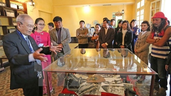 Le Phi, a Da Lat citizen, is introducing visitors to the antique items he donates to the exhibition. (Credit: VN+)