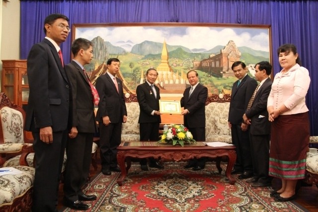 Minister Bosengkham Vongdara presents the friendship medal to outgoing head of Nhan Dan newspaper’s Representative Office in Laos Nguyen Toan Thang.