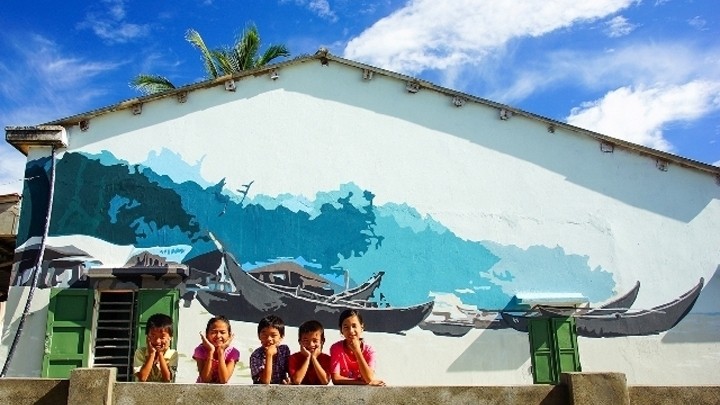 Local children in Trung Thanh village pose in front of a mural by Korean artists 