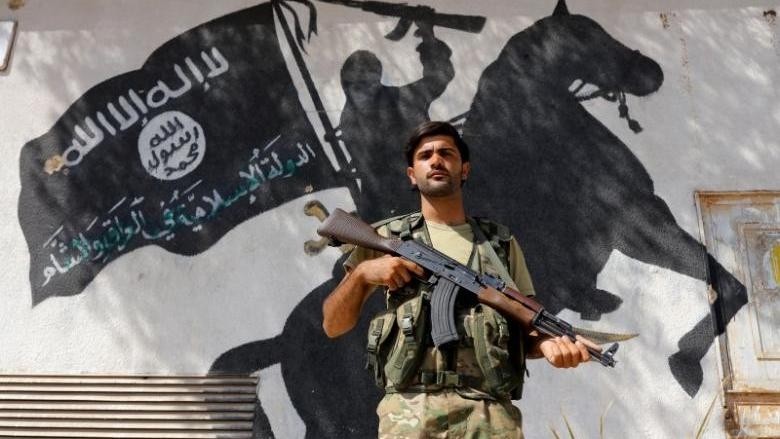 A member of Turkish-backed Free Syrian Army (FSA), seen with a mural of the Islamic State in the background, stands guard in front of a building in the border town of Jarablus, Syria, August 31, 2016. (Credit: Reuters)