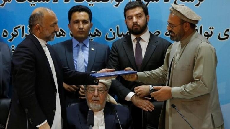 Mohammad Amin Karim (R), representative of Gulbuddin Hekmatyar, and Afghanistan national security adviser Mohammad Hanif Atmar (L) hold a document after signing a peace deal in Kabul, Afghanistan, September 22, 2016. (Credit: Reuters)