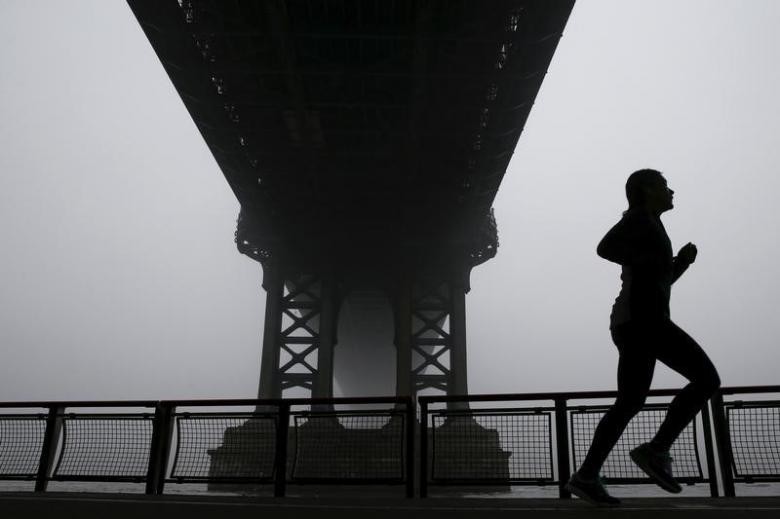 A woman is seen silhouetted while running under the fog covered Manhattan Bridge in New York December 14, 2015. (Photo: Reuters)