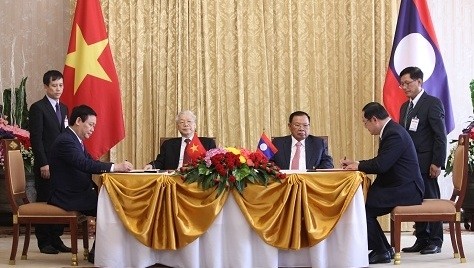 Party General Secretary Nguyen Phu Trong and Party General Secretary and President of Laos Bounnhang Vorachith witness the signing of a MoU on Vietnam’s construction of a parliament building as a gift to Laos.
