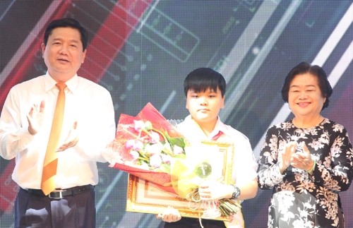 Politburo member and Secretary of the HCM City Party Committee Dinh La Thang (left) presents the certificate to To Huynh Phuc, a sixth grader of the Tran Dai Nghia High School for the Gifted.