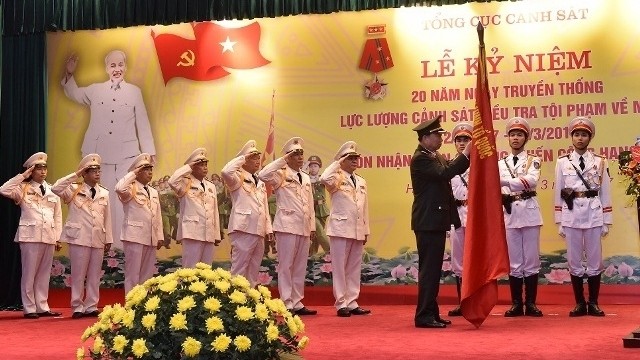 Minister of Public Security Lieutenant General To Lam pins the Feat-of-Arms Order, first class, to the traditional flag of the Police Department for the Investigation of Drug-Related Crimes.