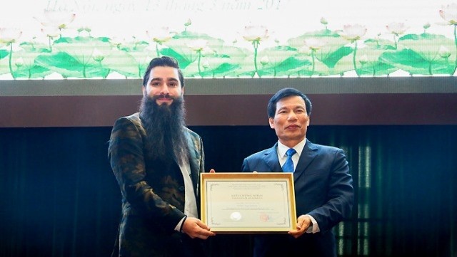 Minister of Culture, Sports and Tourism Nguyen Ngoc Thien hands over the decision of appointing Hollywood film director Jordan Vogt-Roberts as the tourism ambassador of Vietnam for the 2017-2020. (Credit: dulichvn.org.vn)