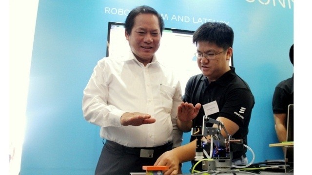 Minister of Information and Communications Truong Minh Tuan controls a robotic arm in real time through the use of hand gestures and fingers at the 5G demonstration in Hanoi on July 12. (Credit: infonet.vn)