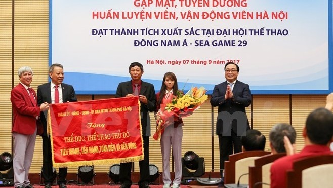 Secretary of the Hanoi Party Committee Hoang Trung Hai (right) presents the emulation flag to Hanoi's SEA Games trainers and athletes.