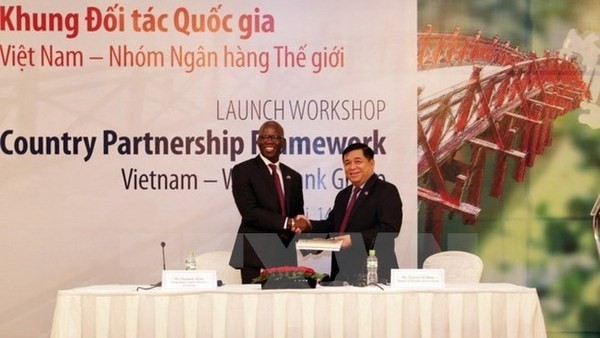 WB Country Director Ousmane Dione (left) hands over the book on the Country Partnership Framework for Vietnam to Minister of Planning and Investment Nguyen Chi Dung (Photo: VNA)
