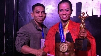 Pham Van Mach (R) poses with Dinh Thi Kim Loan after she wins a gold medal at the World Bodybuilding and Physique Sports Championships (Photo: mediacdn.vn)