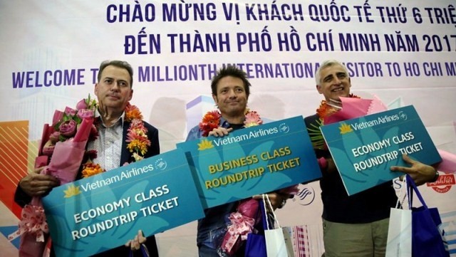 Mitchener David William (C), the six millionth international guest to HCM City in 2017, along with the 5,999,999th and 6,000,001st visitors. (Credit: toquoc.vn)