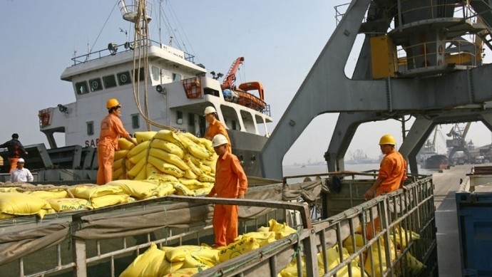 Workers are loading goods onto a cargo ship.