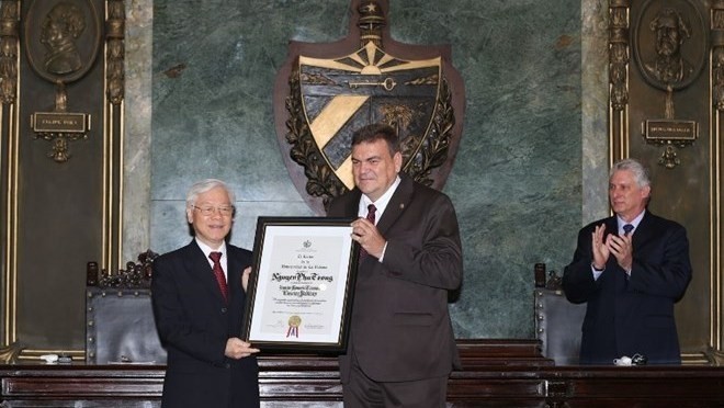 A leader of the University of Havana presents the Doctor Honoris Causa title to CPV General Secretary Nguyen Phu Trong (L) (Photo: VNA)