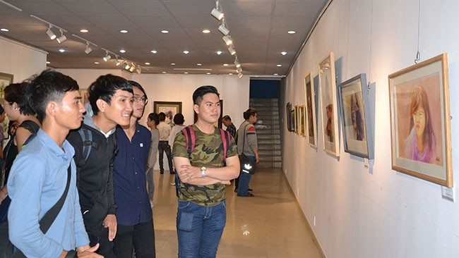 Visitors admiring paintings on display at the exhibition 