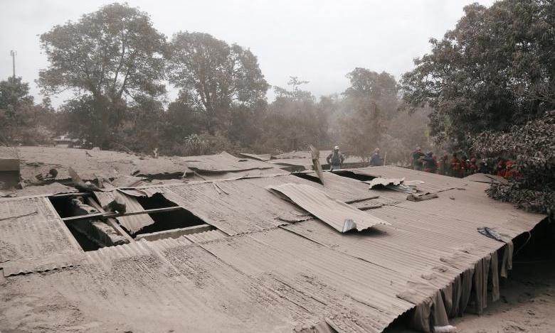 Rescue workers gather next to a roof covered in ash in San Miguel Los Lotes in Escuintla, Guatemala on June 5, 2018. (Photo: Reuters)