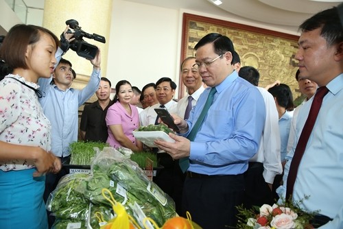 Deputy PM Vuong Dinh Hue uses a mobile phone to trace origins of Bac Giang farm produce (photo: VNA)