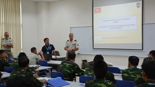 A French expert gives a presentation on international standards for mine action during the exchange. (Photo: qdnd.vn)