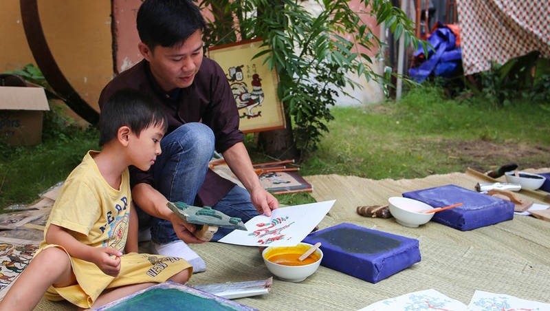 A kid is being instructed on how to make Dong Ho print at an event in Ho Chi Minh City (Image: Zing)