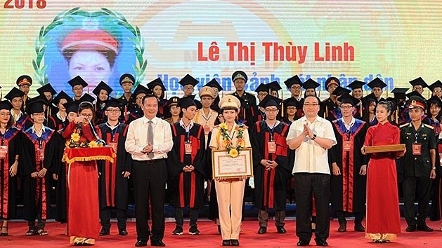 Politburo member and Secretary of Hanoi municipal Party Committee Hoang Trung Hai and Deputy Head of  the Party Central Committee's Commission for Mass Mobilisation Nguyen Nam present certificates of merit to outstanding graduates. 