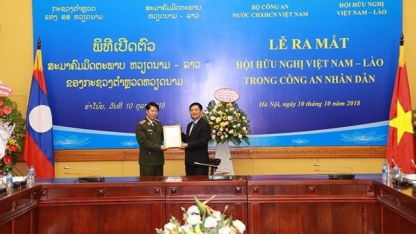 Deputy Head of the Party Central Committee's Organisation Commission cum President of the Vietnam-Laos Friendship Association, Tran Van Tuy (R), hands over the decision on the establishment of the Vietnam-Laos Friendship Association under the People's Police Force to Deputy Minister of Public Security, Bui Van Nam. (Photo: anninhthudo.vn)