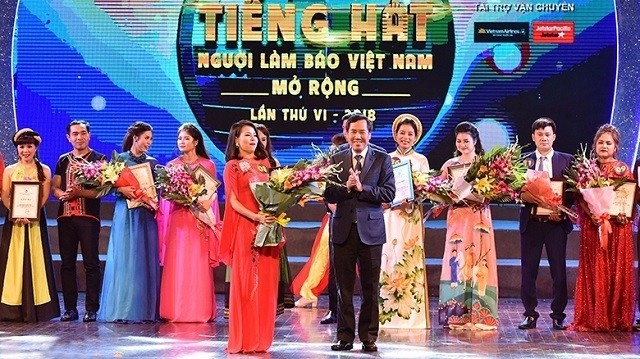 Chairman of the Vietnam Journalists’ Association and Editor-in-Chief of Nhan Dan Newspaper, Thuan Huu (R), congratulates the first prize winner. (Photo: NDO/Dang Anh)