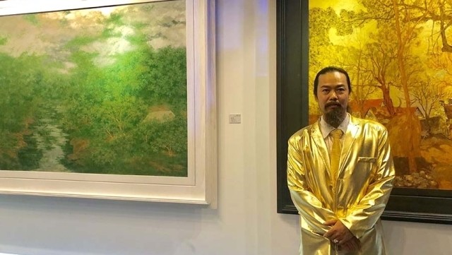 Painter Nguyen Quoc Huy standing in front of his paintings at the opening of the exhibition in Hanoi on October 31. (Photo: NDO/Minh Nhat)