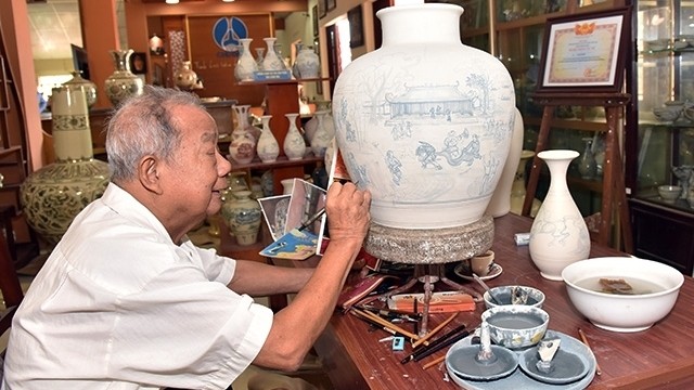 Artisan Ha Ba Dinh draws motifs on Chu Dau ceramic pottery. (Photo: NDO/Dang Anh)