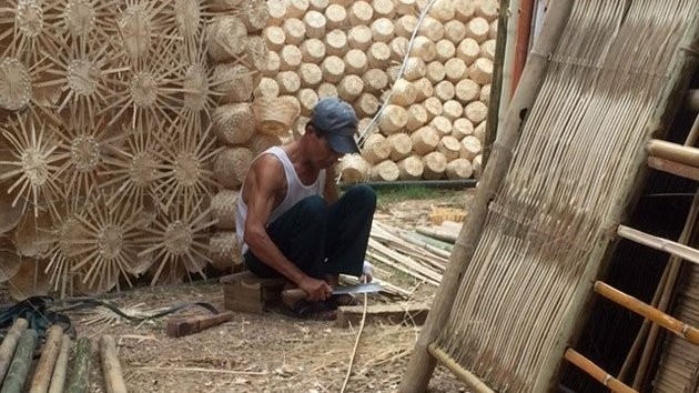 A craftsman from Phu Vinh village working on a rattan-made house built in the shape of a cloud. 