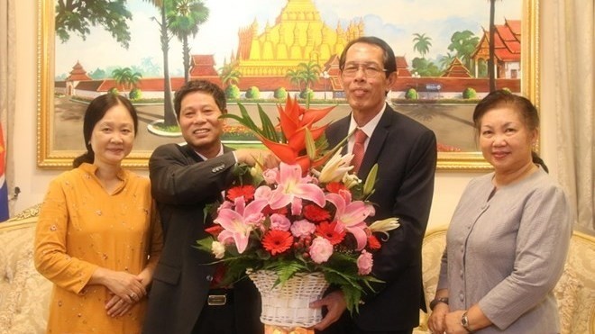 Ambassador Le Quy Quynh (centre, L) presents a flower basket to representatives of the Lao Embassy (Photo: VNA)