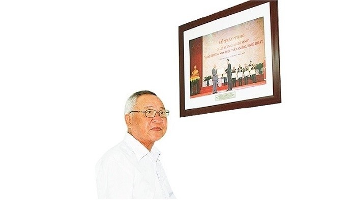Composer Hinh Phuoc Long with a photo captured when he was granted the Ho Chi Minh Prize - the State Prize for Literature and Arts, in 2017. (Photo: NDO/Le Duc Quang)
