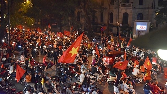 Downtown streets in Hanoi crowded with long lines of people flying high the national flags.
