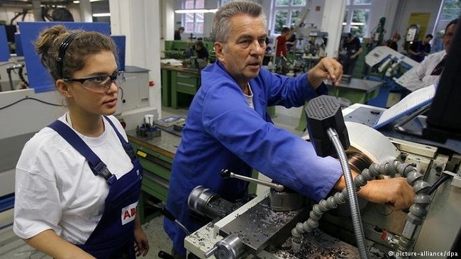 A man and a woman work on a machine in a factory (Photo: DPA)